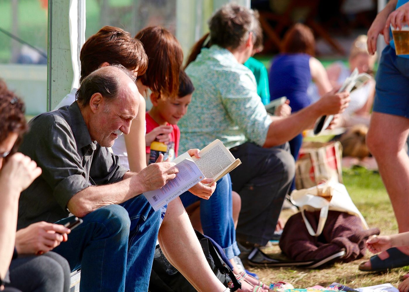 Festival-goers sit on the grass reading and talking at Hay Festival in Hay-on-Wye