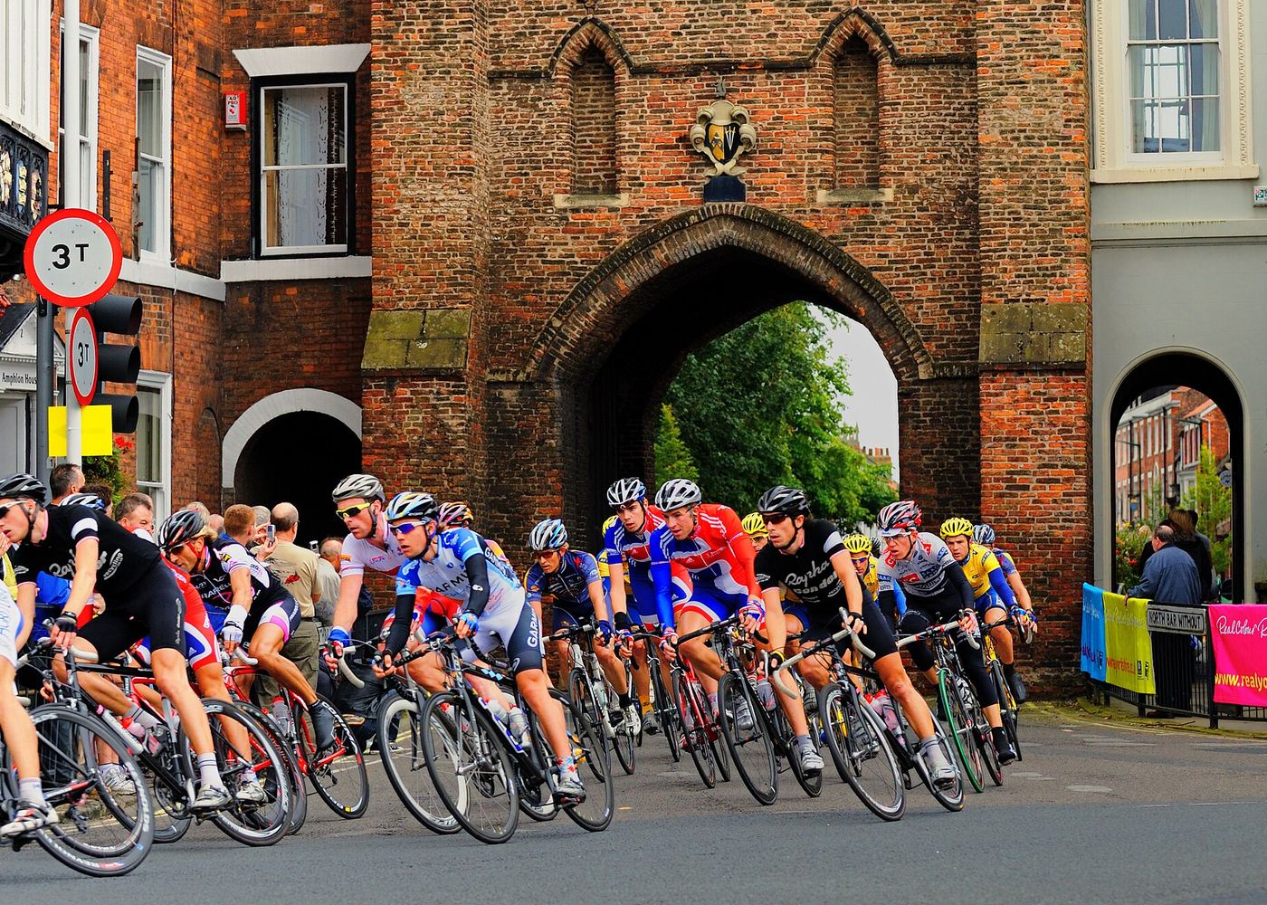 Professional cyclists race through Beverley Bar while spectators watch from the roadside